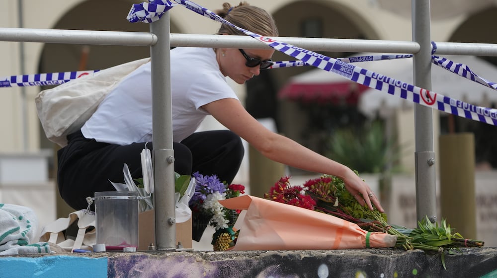 Shenna McClean lays flowers at a memorial at Sydney's Bondi Beach, Monday, Dec. 15, 2025, a day after a shooting. (AP Photo/Mark Baker)