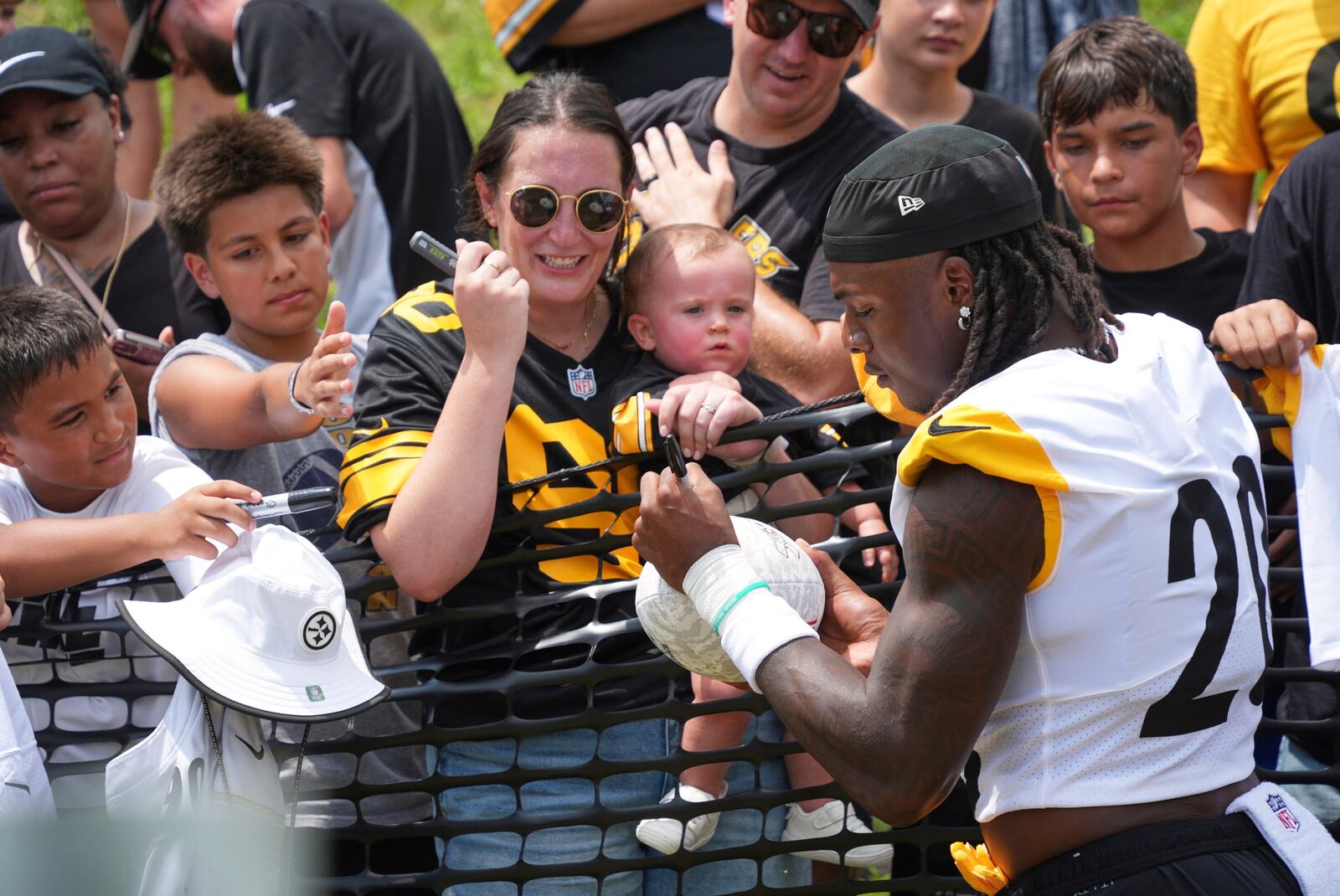 Pittsburgh Steelers running back Kaleb Johnson (20) signs a football for a fan before taking the practice field at the NFL football training camp in Latrobe, Pa., Saturday, July 26, 2025. (AP Photo/Gene J. Puskar)