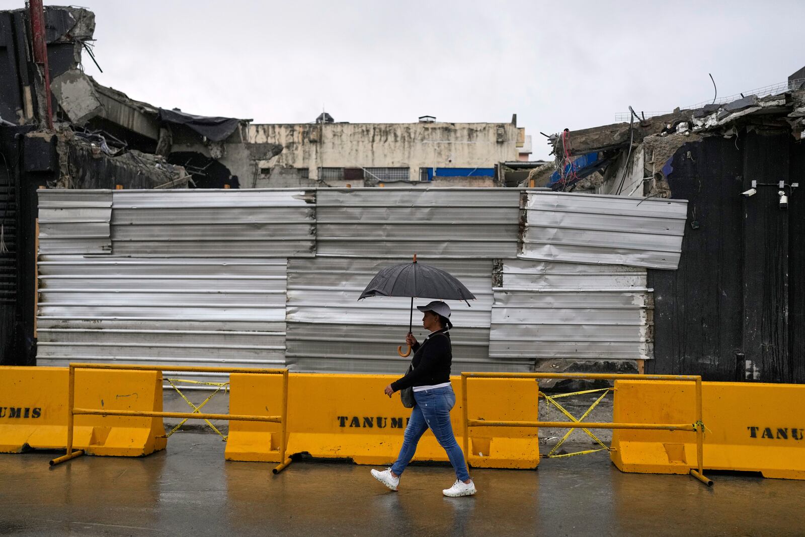 A woman walks past the rubble of Jet Set nightclub days after its roof collapsed, killing more than 200 people, in Santo Domingo, Dominican Republic, Friday, April 11, 2025. (AP Photo/Matias Delacroix)