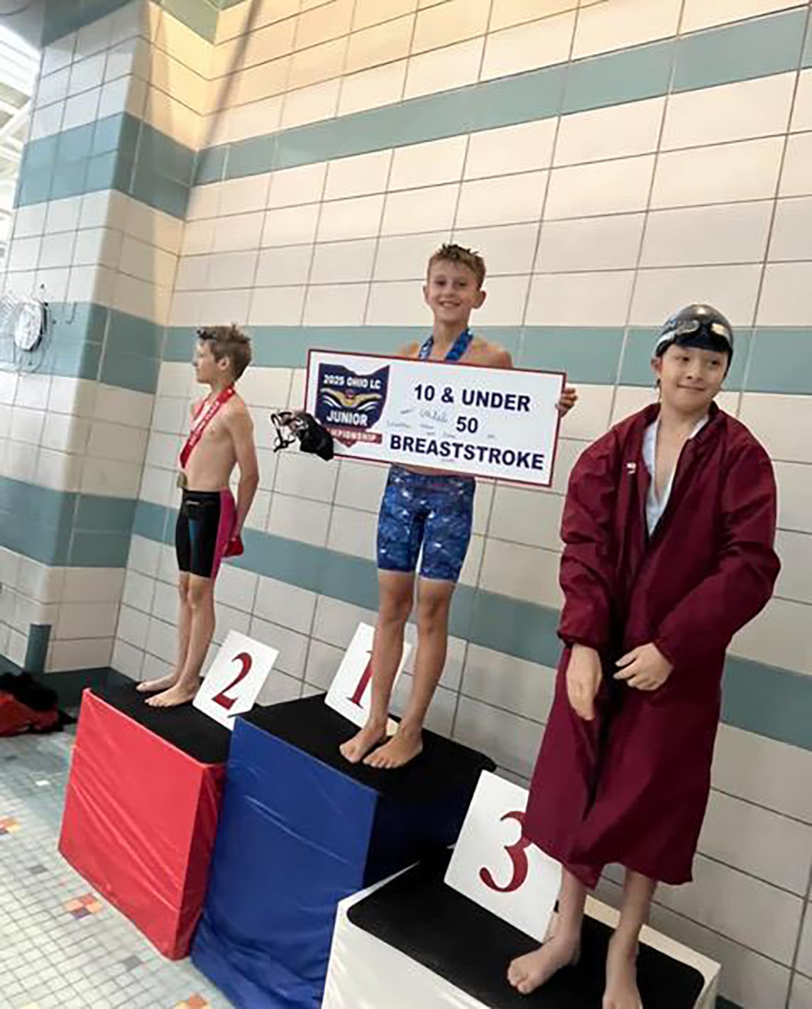 Tyler Gibble (center) at Miami University showing off his win for the 50 meter breastroke. CONTRIBUTED