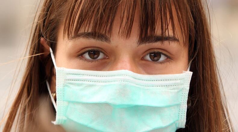 A woman wearing a surgical mask to prevent the transmission of airborne infection in London, England.