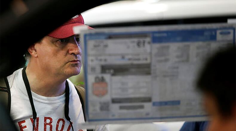 In this Monday, Oct. 9, 2017, photo, a man looks at the sticker price of a pickup truck on display at the State Fair of Texas in Dallas. America’s favorite luxury vehicle is a pickup truck. Buyers are increasingly outfitting their pickups with all the comforts of luxury cars, from heated and cooled seats to backup cameras to panoramic glass roofs. (AP Photo/LM Otero)