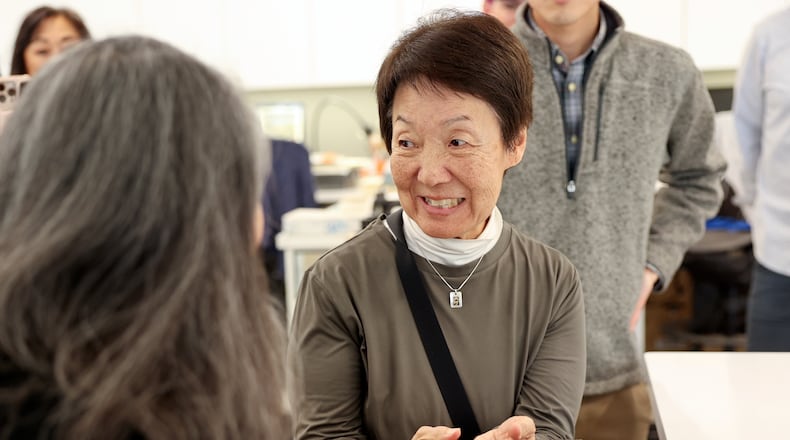 Karen Okawa, Japanese Church of Christ member and time capsule committee member, reacts as she holds a heavy lid that was used on the Japanese Church of Christ's 100-year-old time capsule at the University of Utah Marriott Library Preservation Department in Salt Lake City, Monday, Oct. 20, 2025. (Kristin Murphy/The Deseret News via AP)