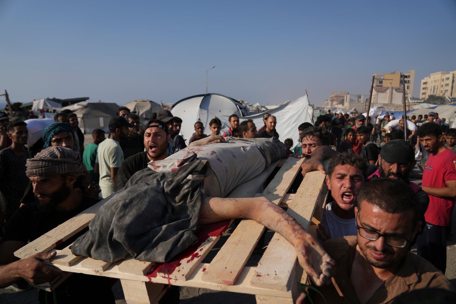 Palestinians carry the body of a man who was killed while trying to reach humanitarian aid trucks that entered Gaza City from the northern Gaza Strip, Saturday, July 26, 2025. (AP Photo/Abdel Kareem Hana)