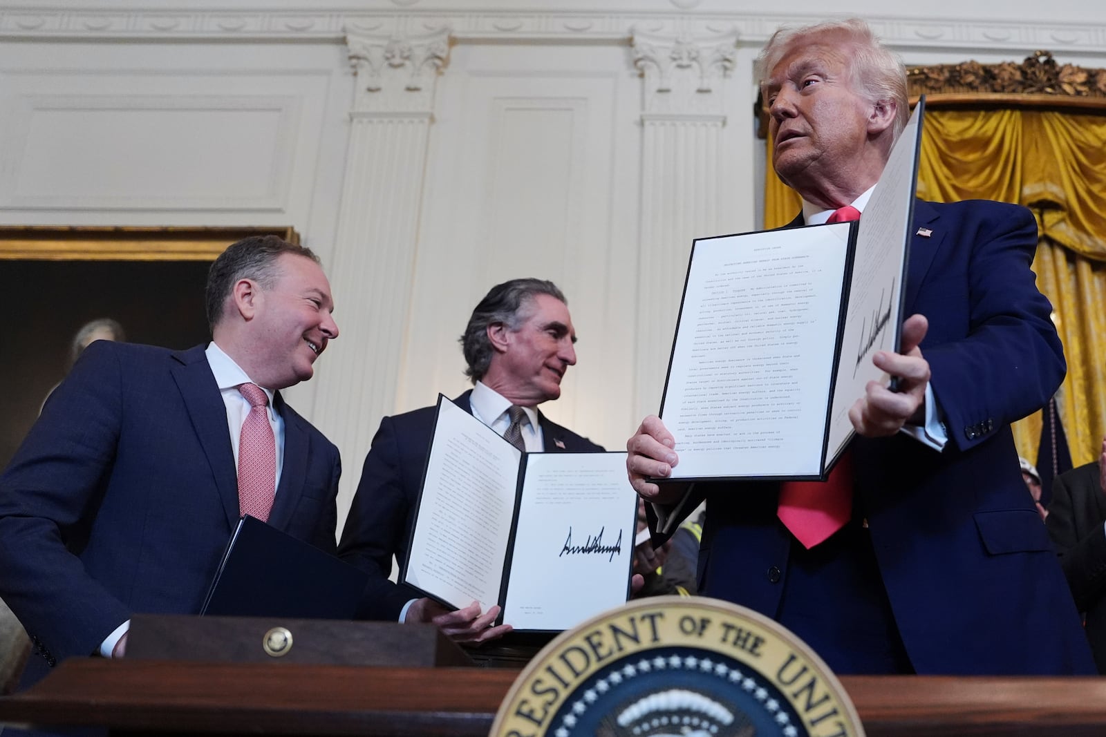 President Donald Trump holds a signed an executive order during an event in the East Room of the White House, Tuesday, April 8, 2025, in Washington, as Environmental Protection Agency director Lee Zeldin and Interior Secretary Doug Burgum watch. (AP Photo/Evan Vucci)