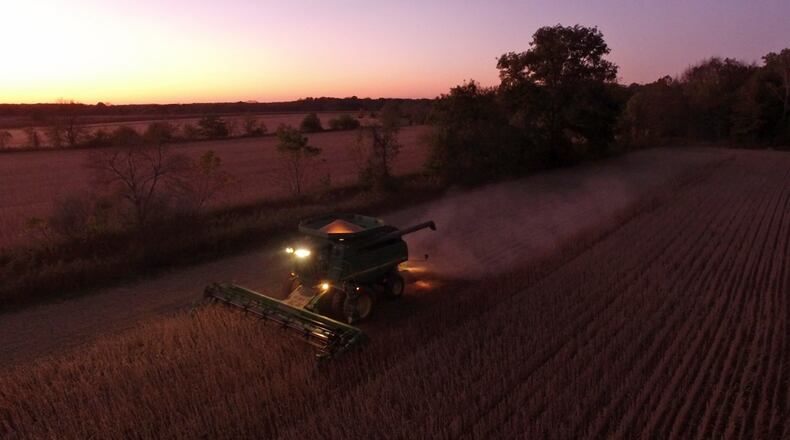 Gary Mason and his son, Chad Mason, harvest soybeans in a field they farm on New Burlington Road in Clinton County at twilight in this October 2017 photo. TY GREENLEES / STAFF