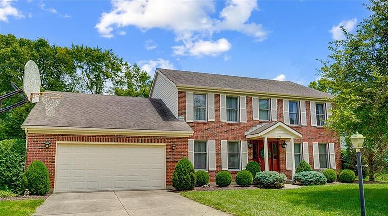 The front of the brick traditional two story has a two car attached garage with overhead storage and opener. The front porch has a covered portico.