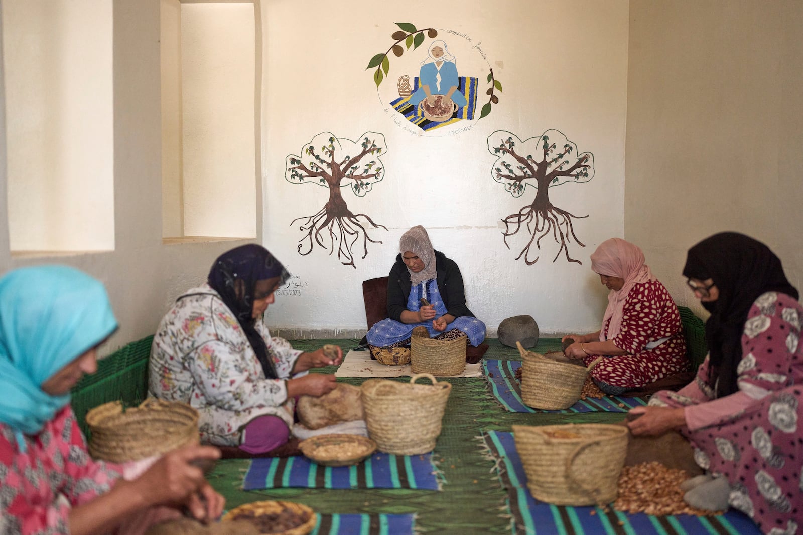 Women crack argan nuts at a cooperative that extracts and produces argan oil and products, in Essaouira, Morocco, Thursday, May 22, 2025. (AP Photo/Mosa'ab Elshamy)