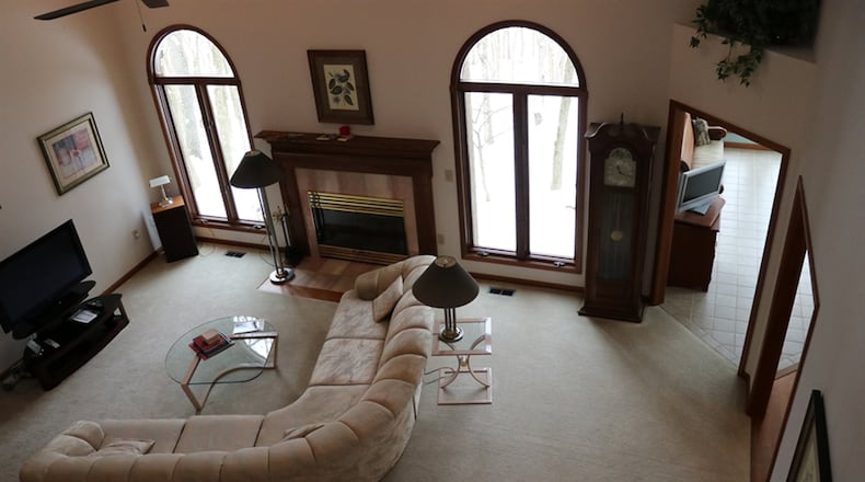 A vaulted ceiling rises 2 stories above the great room. Enhanced with tile facing and a wood mantel, the fireplace is flanked by tall double casements arranged with arched transoms and rounded casings.