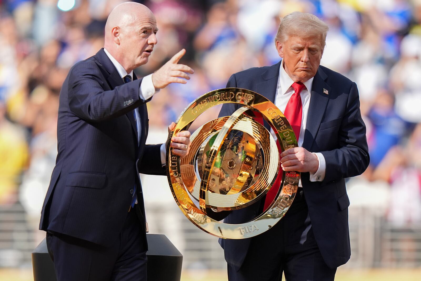 FIFA President Gianni Infantino, left, and President Donald Trump carry the championship trophy after the Club World Cup final soccer match between Paris Saint-Germain and Chelsea in East Rutherford, N.J., Sunday, July 13, 2025. (AP Photo/Frank Franklin II)