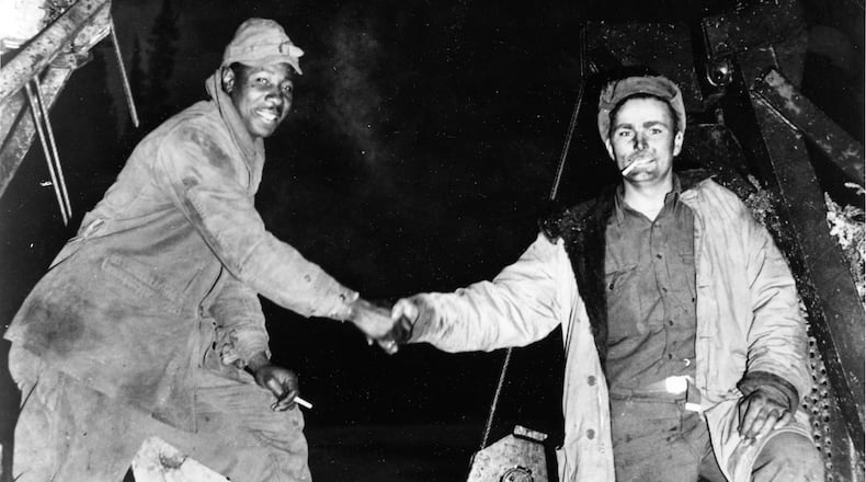 FILE - This Oct. 25, 1942, photo provided by the U.S. Army Corps of Engineers Office of History, shows Corporal Refines Slims, Jr., left, and Private Alfred Jalufka shaking hands at the, "Meeting of Bulldozers," for the ALCAN Highway in the Yukon Territory in Beaver Creek, Alaska. (U.S. Army Corps of Engineers Office of History via AP, File)