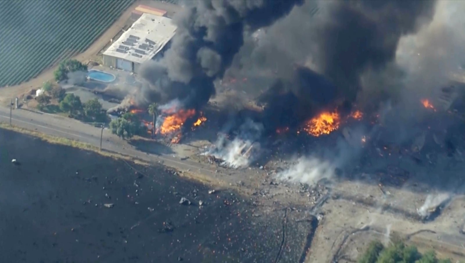 In this aerial image taken from video, smoke and flames rise from a fireworks warehouse explosion, July 1, 2025. (KGO via AP)