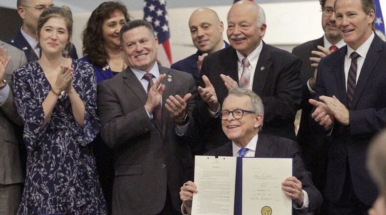 Gov. Mike DeWine signed Ohio Senate Bill 7 in January 2020 during a ceremony at the National Museum of the U.S. Air Force. The bill mandates state occupational licensing agencies issue temporary licenses and certificates to members of the military and spouses who are licensed in another jurisdiction and have moved to Ohio for military duty. From left to right are Brianna McKinnon, a military spouse and special education teacher, Rep. Rick Perales, Sen. Bob Hackett and Lt. Gov. Jon Husted. LISA POWELL / STAFF