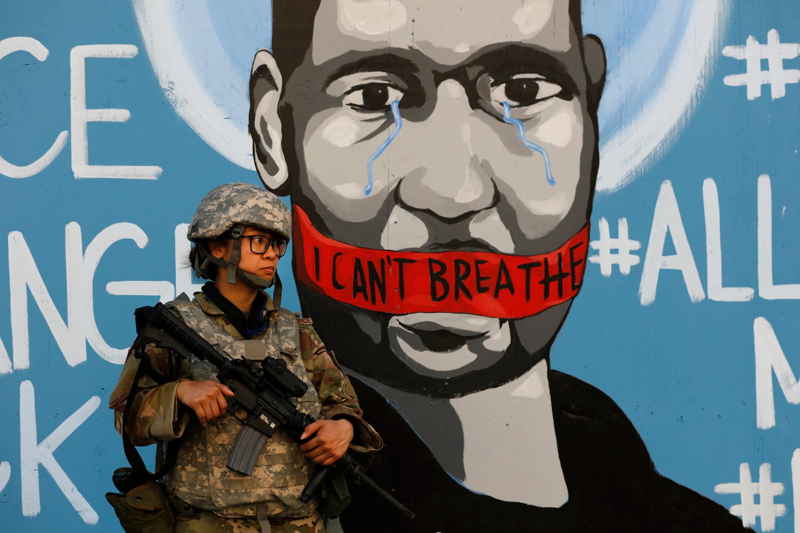 FILE — In this June 4, 2020 file photo a member of the California National Guard stands in front of a mural depicting George Floyd in Los Angeles. On Thursday June 11, 2020, California Gov. Gavin Newsom's Administration announced it cost more than $24 million to deploy 8,000 National Guard members for 18 days during the recent protests of racial injustice inspired by the death of Floyd on May 25 in Minneapolis. (AP Photo/Jae C. Hong, File)