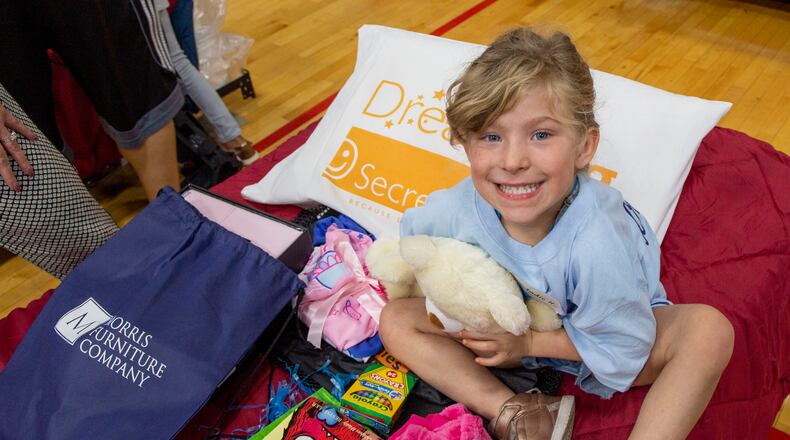 A child just receiving a bed hugs a stuffed animal during the Day to Dream event in 2019.