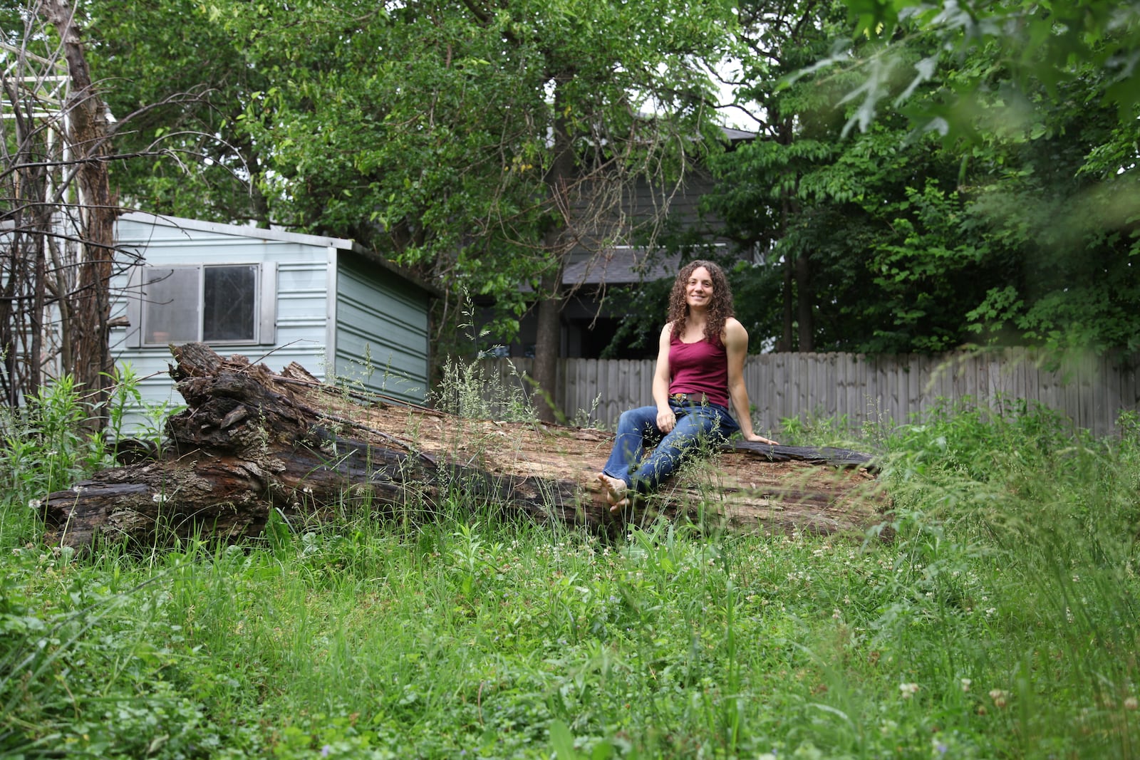 Amanda Beltranmini Healen poses on a fallen log in her backyard in Nashville, Tenn., Monday, May 19, 2025, where she participates in No Mow Months to improve water retention and encourage pollinators. (AP Photo/Kristin M. Hall)