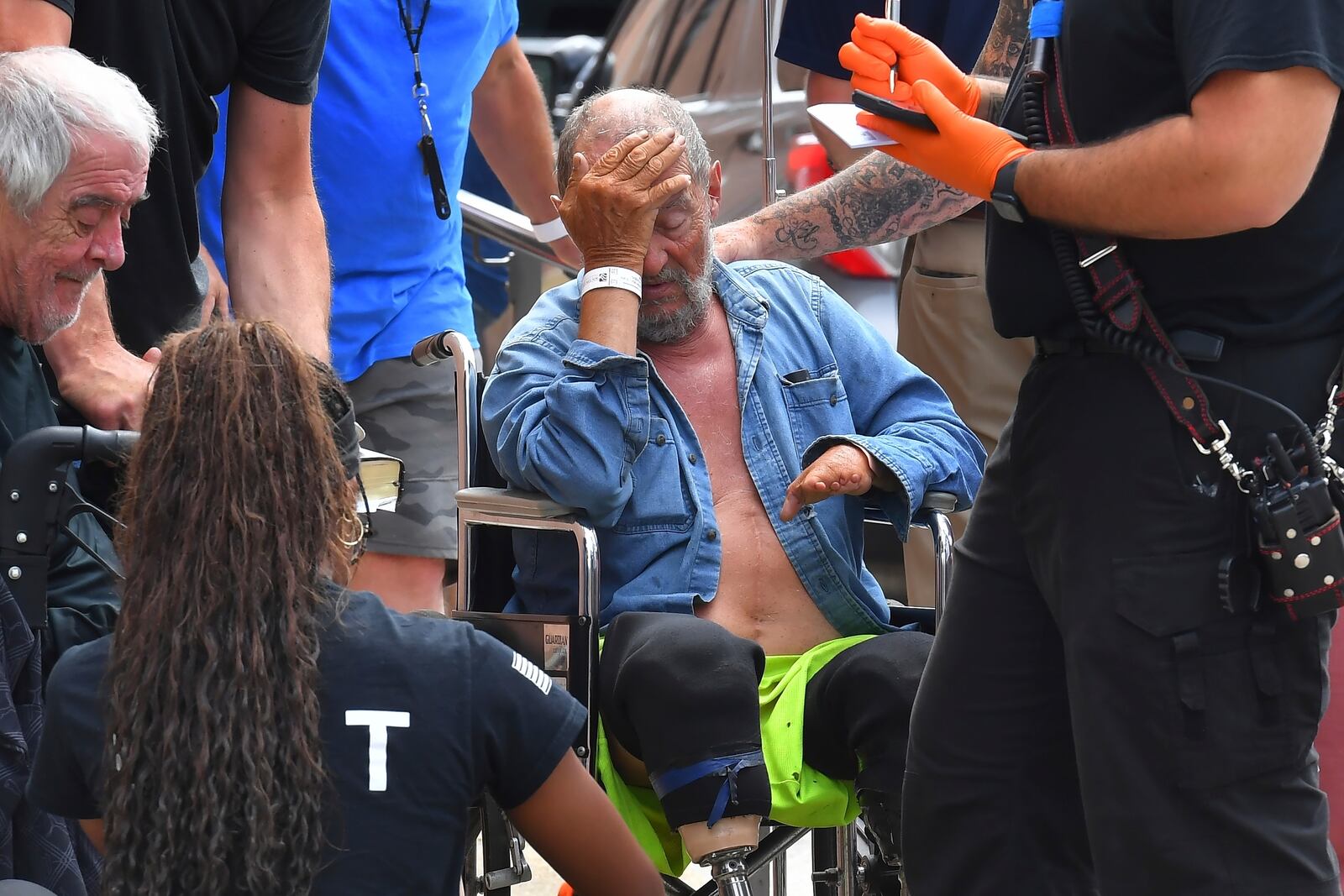 Michael Pimentel, center, a resident at the Gabriel House assisted living facility, in Fall River, Mass., receives assistance from an emergency medical worker, right, outside a temporary shelter, Monday, July 14, 2025, in Fall River, following a fire that started late Sunday. (AP Photo/Steven Senne)