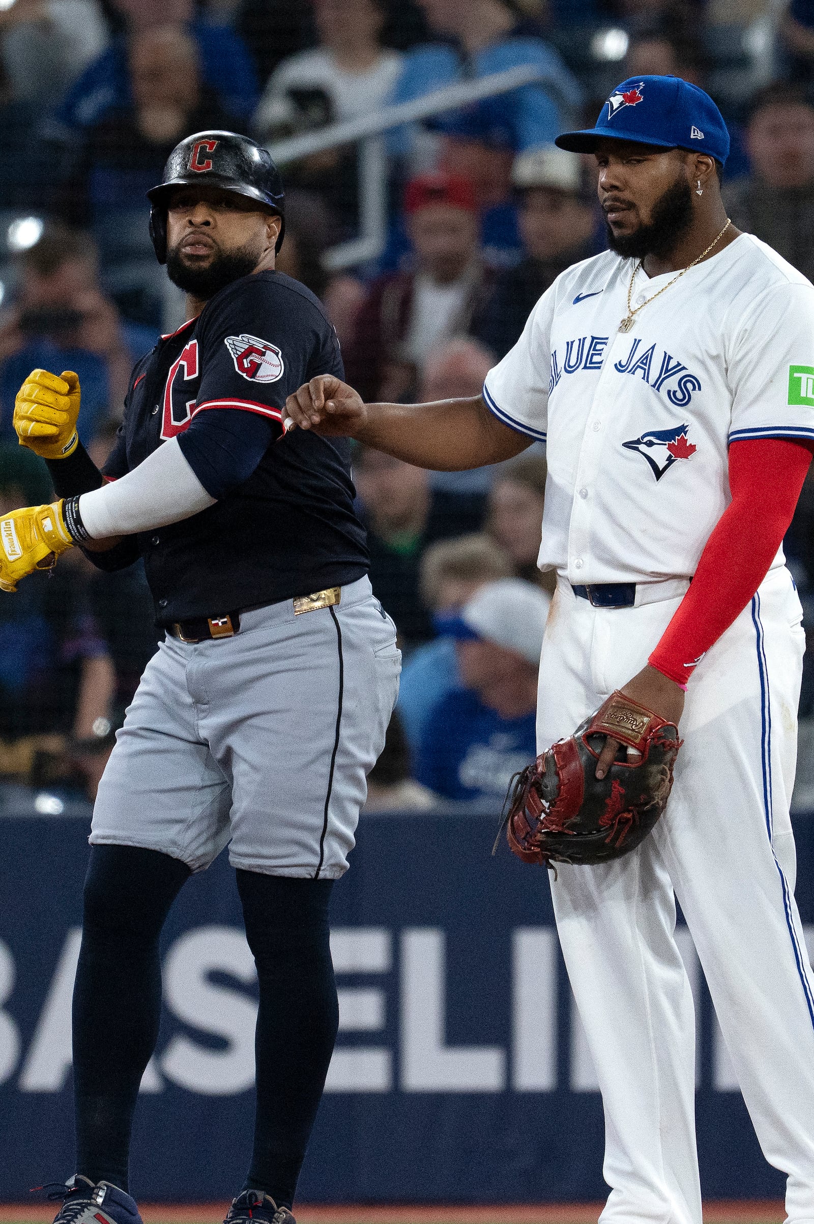 Cleveland Guardians Carlos Santana, left, jokes with Toronto Blue Jays first baseman Vladimir Guerrero Jr during the first inning of a baseball game in Toronto, Saturday, May 3, 2025. (Jon Blacker/The Canadian Press via AP)