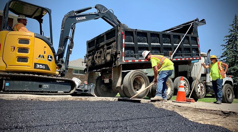 Working with 250 degree asphalt on a 100 degree Wednesday June 15, 2022 makes for hot day for these workers for MIller Pipeline in Dayton. MARSHALL GORBY\STAFF