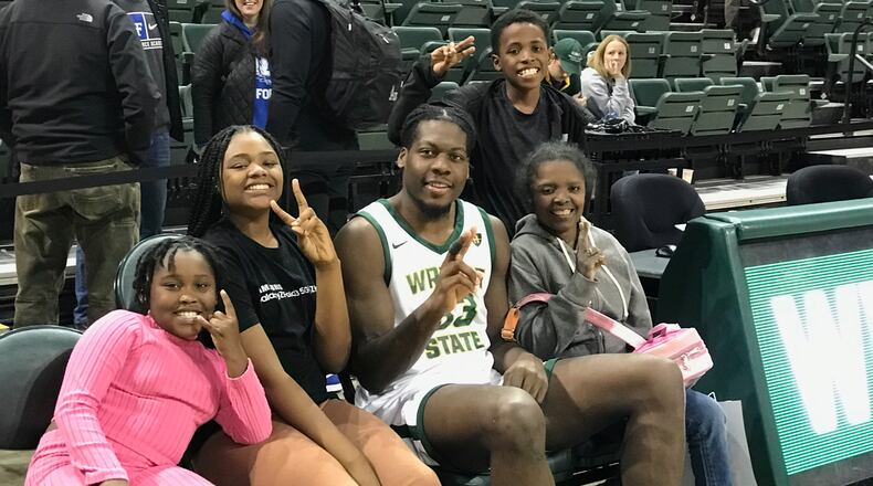 Telling him “you’re our favorite player,” Wright State fans (left to right) nine-year-old Aniya Quinn; 13-year-old Raven Mills; Markise Martin, who’s 11; and their aunt Taccara Nelson pose on the Raiders bench with WSU forward Michael Imariagbe after WSU’s 70-57 victory over Air Force Saturday night at the Nutter Center. Imariagbe made all six of his shots in the game for 14 points Tom Archdeacon/CONTRIBUTED