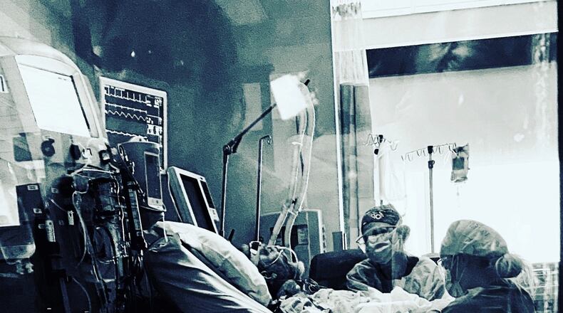 Lindsey Fairchild, an ICU nurse in Florida, took this photo of her father, Wayne Oney, on the day he died at Atrium Medical Center. His wife, Lisa, can be seen in the window reflection. SUBMITTED PHOTO