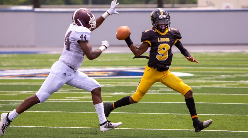 Meadowdale quarterback Tre Hodge looks to pass under pressure from Cincinnati Western Hills' Walter Womack during Saturday's game at Welcome Stadium.