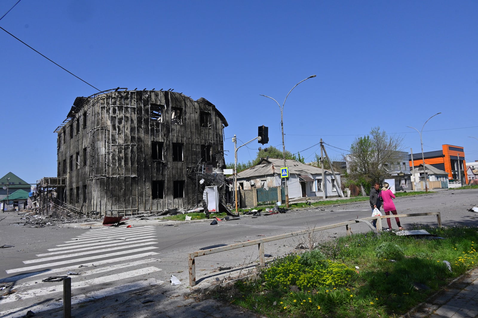 Local residents walk past damaged buildings in central Pokrovsk, the site of the heaviest battles with the Russian troops in the Donetsk region, Ukraine, Wednesday, April 23, 2025. (AP Photo/Michael Shtekel)