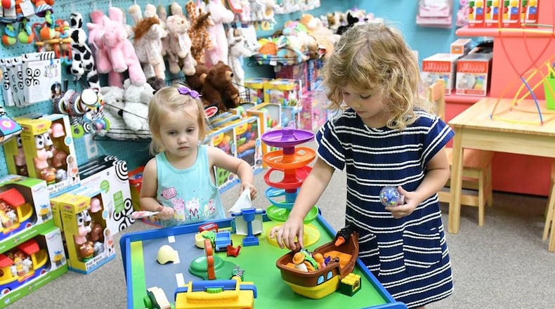 Sisters Mae Smith, 2, and Aura Smith, 3 1/2, check out some of the offerings at downtown Tipp City’s Topsy Turvy Toys. CONTRIBUTED