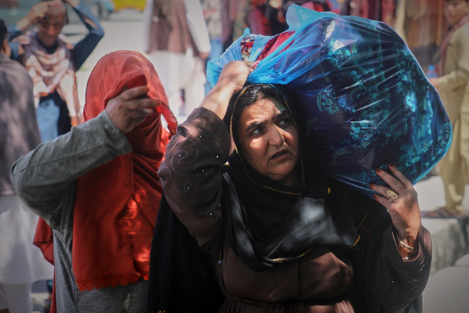 A woman carries a plastic bag on her shoulder at a central market in Kabul, Afghanistan, Tuesday, April 15, 2025. (AP Foto/Siddiqullah Alizai)
