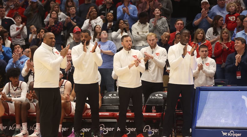Dayton coaches applaud as Doug Hauschild, who is retiring after the school year, is honored during a timeout in the second half  against Loyola Chicago on Saturday, Jan. 18, 2025, at UD Arena. David Jablonski/Staff
