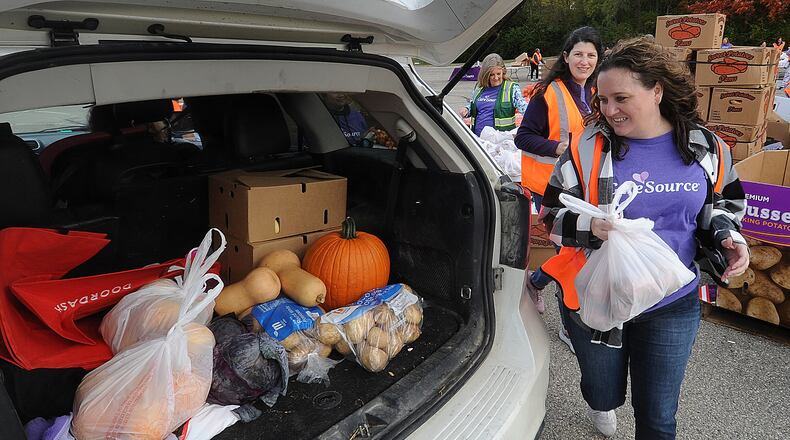 CareSource employees from left, Denise Johnson, Megan Post and Emily Smith place food into the back of a SUV Thursday, Oct. 19, 2023, at the mass food distribution at Wright State University’s Nutter Center. MARSHALL GORBY\STAFF