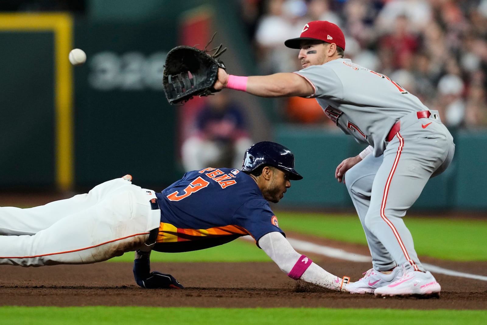 Houston Astros' Jeremy Pena (3) dives back to first base ahead of a throw to Cincinnati Reds first baseman Spencer Steer (7) during the first inning of a baseball game in Houston, Sunday, May 11, 2025. (AP Photo/Ashley Landis)