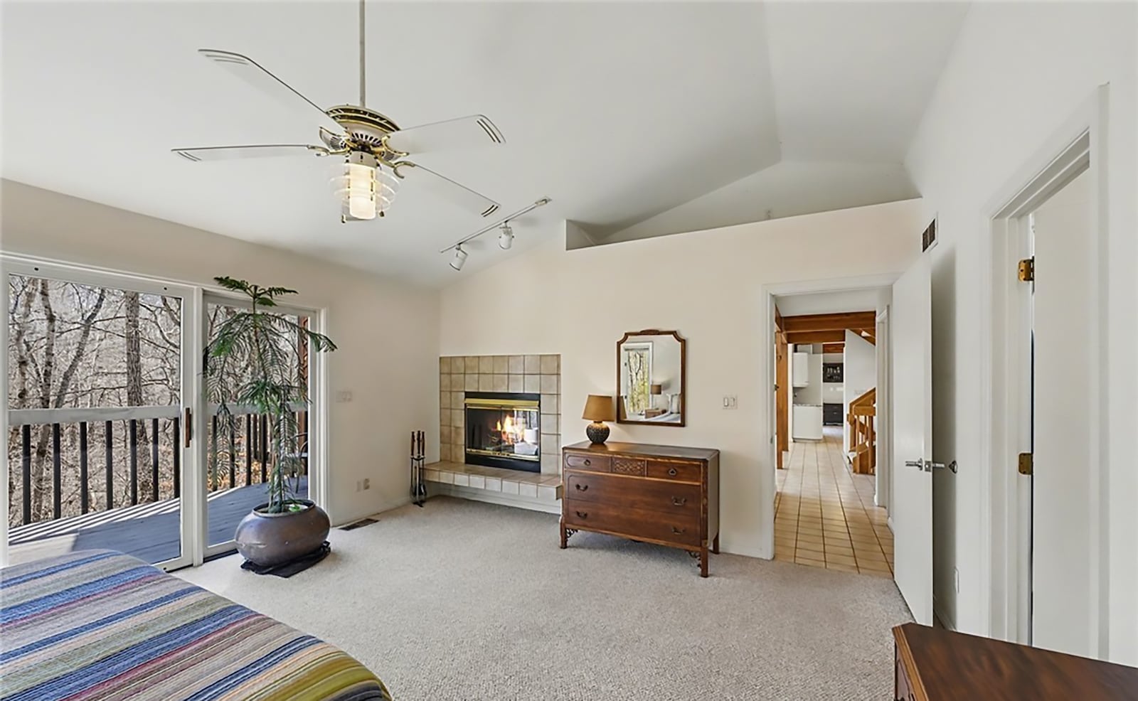 The main floor primary bedroom suite has a double sided woodburning fireplace, vaulted ceiling, ceiling fan, ensuite bathroom and sliding glass doors opening to a deck with railings. CONTRIBUTED