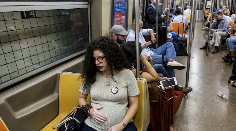 Jamie Tzioumis commutes wearing a “Baby on Board” button, in New York City, Sept. 20, 2017. The button is part of a new campaign by the Metropolitan Transportation Authority to encourage commuters to give up seats for passengers who are pregnant, older or have a disability. Does the button work on a crowded train? According to Tzuioumis, who is six months pregnant, not really. CHRISTIAN HANSEN/THE NEW YORK TIMES