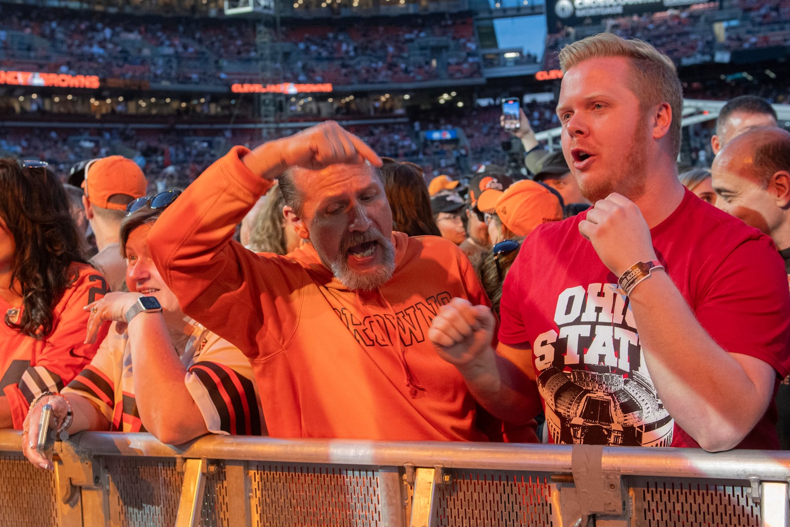 Fans Mike Dillion, center, of Vermillion, Ohio, and Garrett McKinney, right, of Amherst, Ohio, react after the Cleveland Browns traded their first-round draft pick during the Browns NFL football draft party in Cleveland, Thursday, April 24, 2025. (AP Photo/Phil Long)