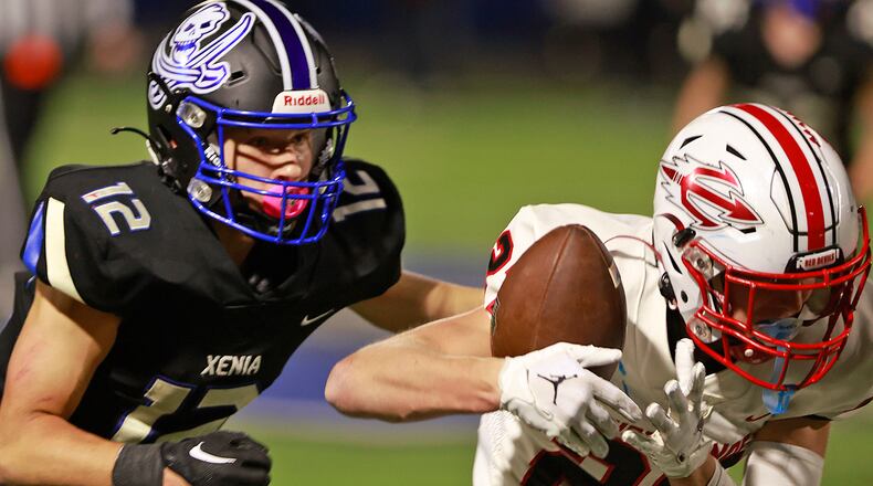 Tipp's Grant Titley catches a pass under pressure from Xenia's Laithan Partee during Friday's game. BILL LACKEY/STAFF
