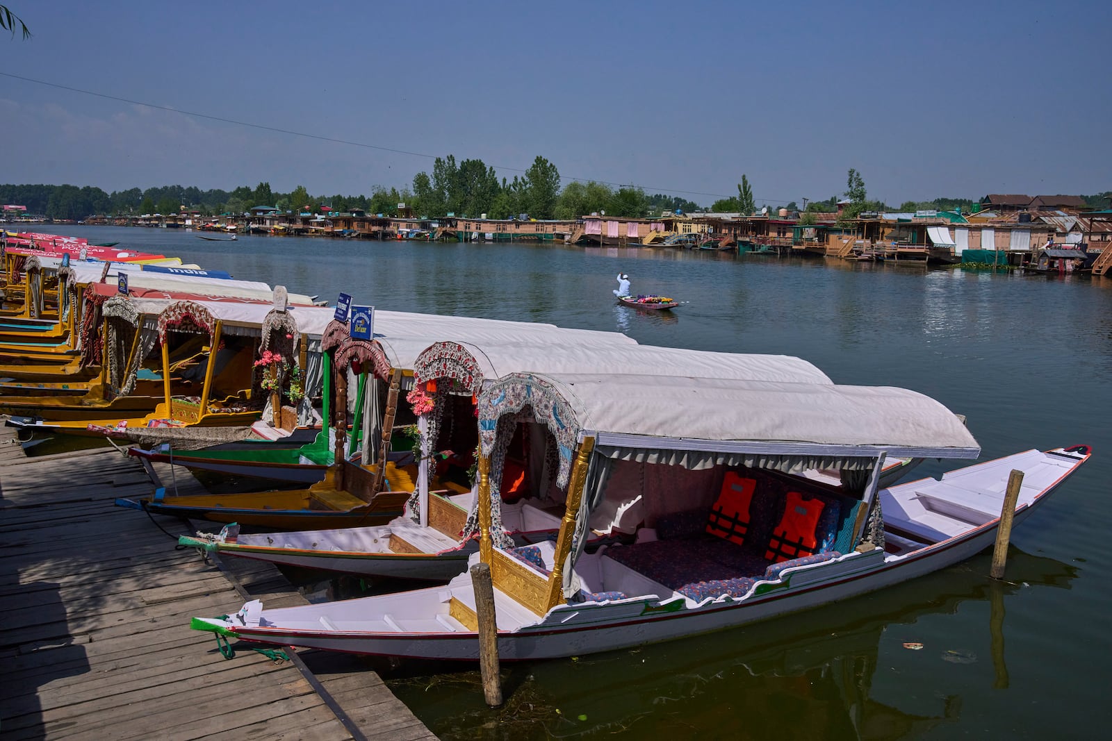 A Kashmiri flower vendor rows past anchored Shikaras, or traditional wooden boats, on Dal Lake in Srinagar, Indian controlled Kashmir, India, Tuesday, May 20, 2025. (AP Photo/Dar Yasin)