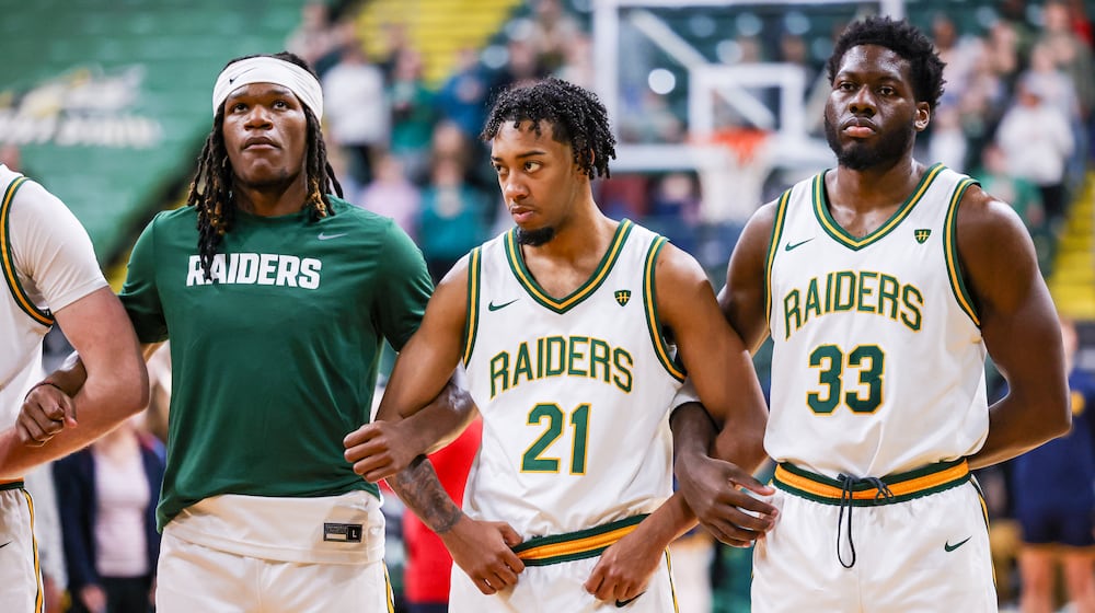 Wright State junior guard Logan Woods (center) links arms with sophomore wing Andrea Holden (left) and graduate forward
Michael Imariagbe (right) during the national anthemn before an 86-37 win over Franklin College 86-37 in a season opener on Monday, Nov. 3 at Ervin J. Nutter Center in Fairborn. BRYANT BILLING/STAFF