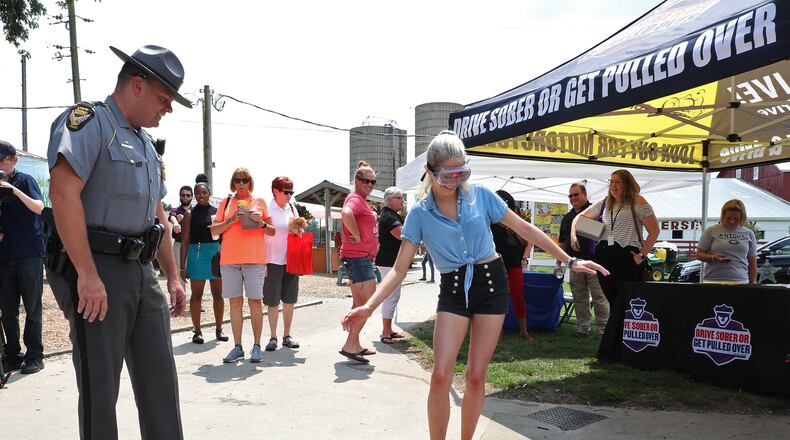 Lt Brian Aller of the Ohio State Highway Patrol has a woman perform a basic sobriety test while wearing impaired driving goggles Tuesday during the Drive Sober or Get Pulled Over kick-off at Young's Jersey Dairy. BILL LACKEY/STAFF