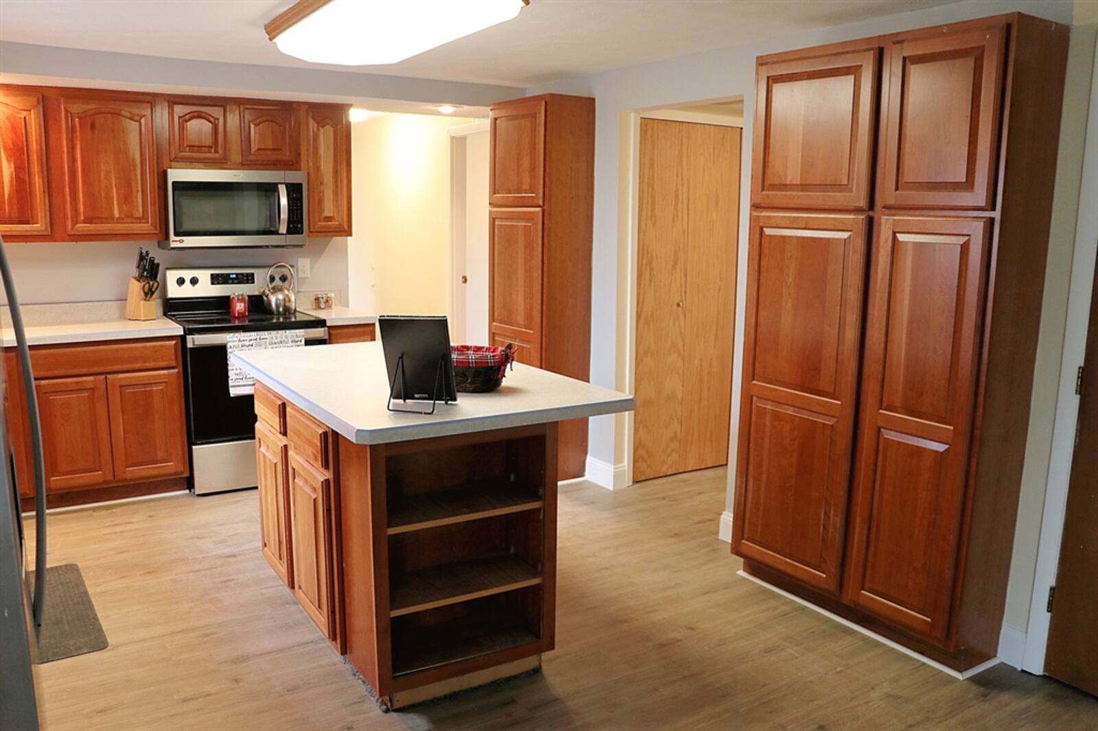 In the kitchen, an island has an extended counter to allow for bar seating for two, and the cabinetry has storage and open book shelves. 