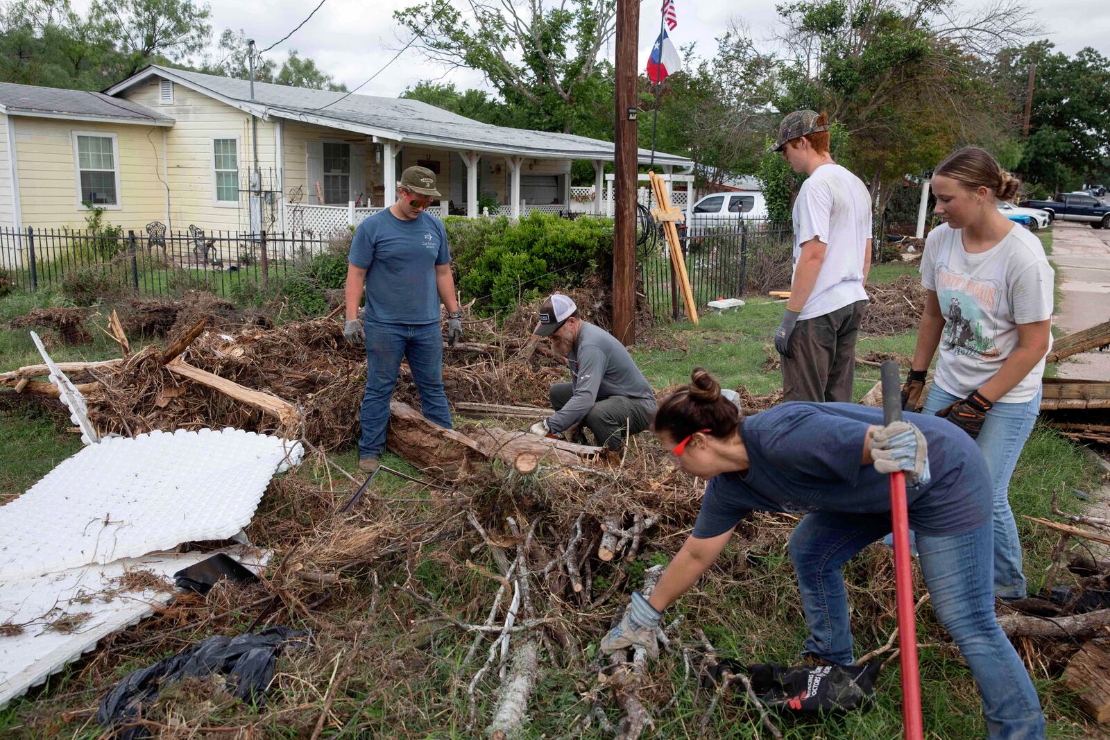 Volunteers from Kerrville Bible Church saw and haul tree debris in front of a flood-damaged home on Guadalupe Street in Kerrville, Texas, on Saturday, July 12, 2025. (AP Photo/Gabriela Aoun Angueira)