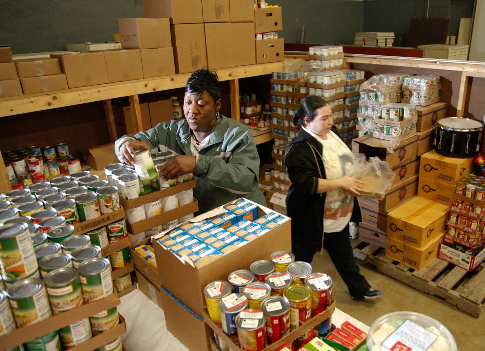 The Wesley Community Center is one of the non-profit agencies who distribute food from The Food Bank to those in need.... Volunteers Jessica Stone of Dayton (left) and Jenny McGuire keep the food pantry stocked. McGuire also uses the pantry.
