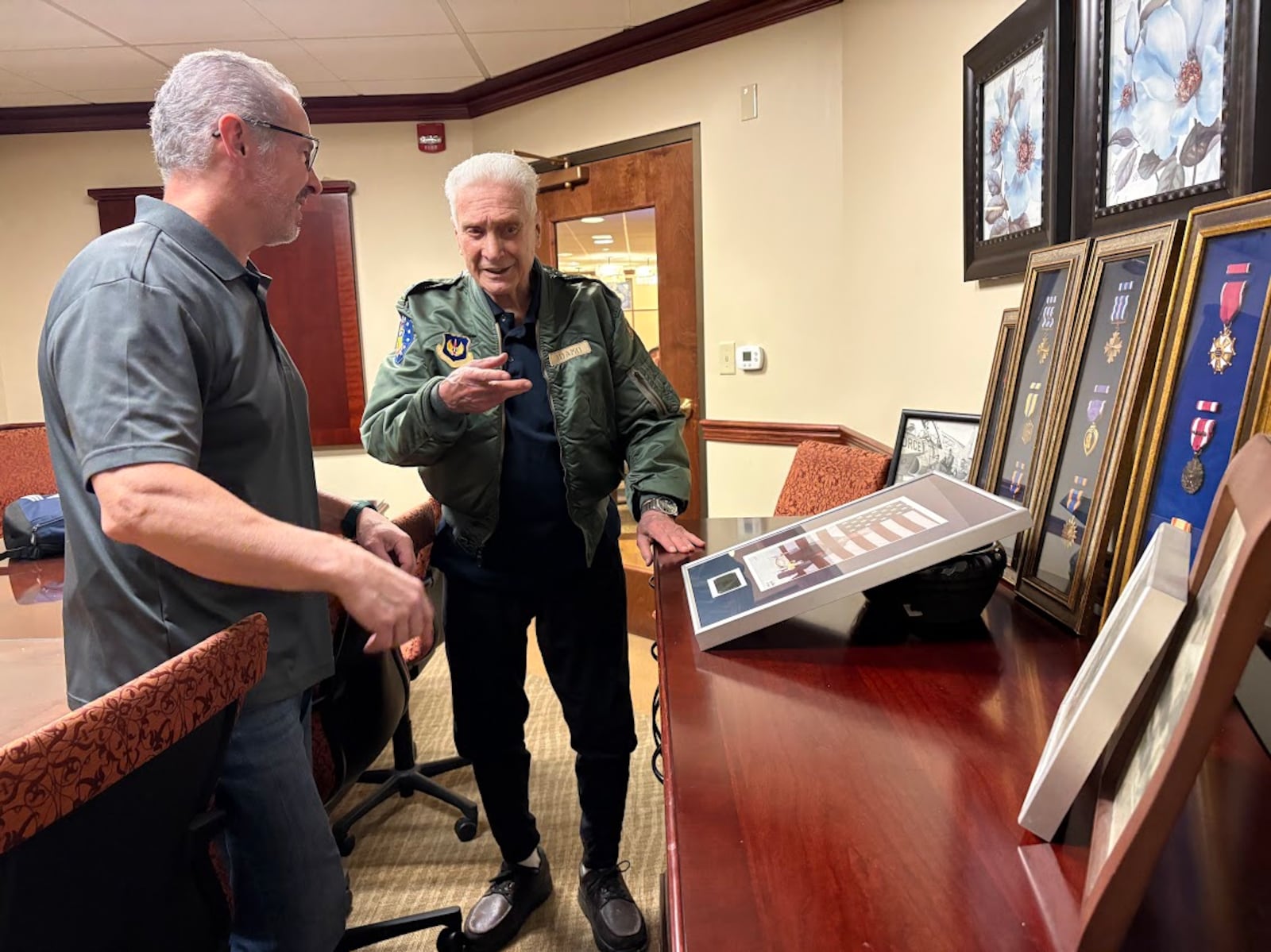 Joseph Adamo, center, with a few of his service medals. His son, also Joseph Adamo, stands to the left. The older Mr. Adamo, a resident of 10 Wilmington Place retirement community, celebrates his 100th birthday Feb. 11. THOMAS GNAU/STAFF