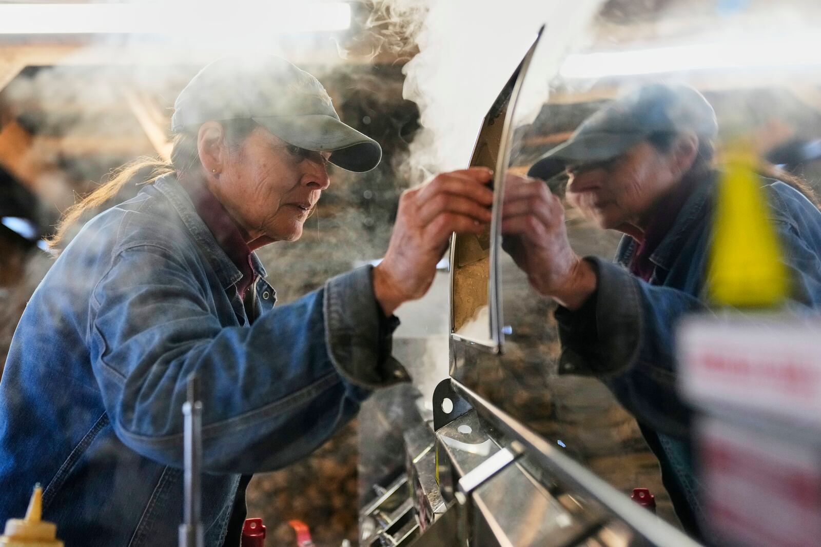Donna Young checks the Canadian-made maple syrup evaporator in the sugarhouse at Judd's Wayeeses Farms in Morgan, Vt., on Friday, April 11, 2025. (AP Photo/Robert F. Bukaty)