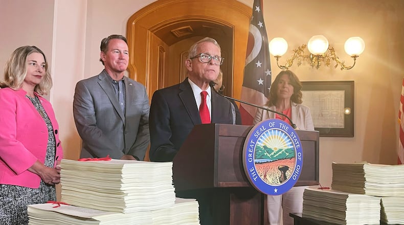 Ohio Gov. Mike DeWine, surrounded by the over 6,000 pages making up Ohio's $86 million state budget, addresses reporters at a press conference, Wednesday, July 5, 2023, at the Ohio Statehouse in Columbus, Ohio. (AP Photo/Samantha Hendrickson)
