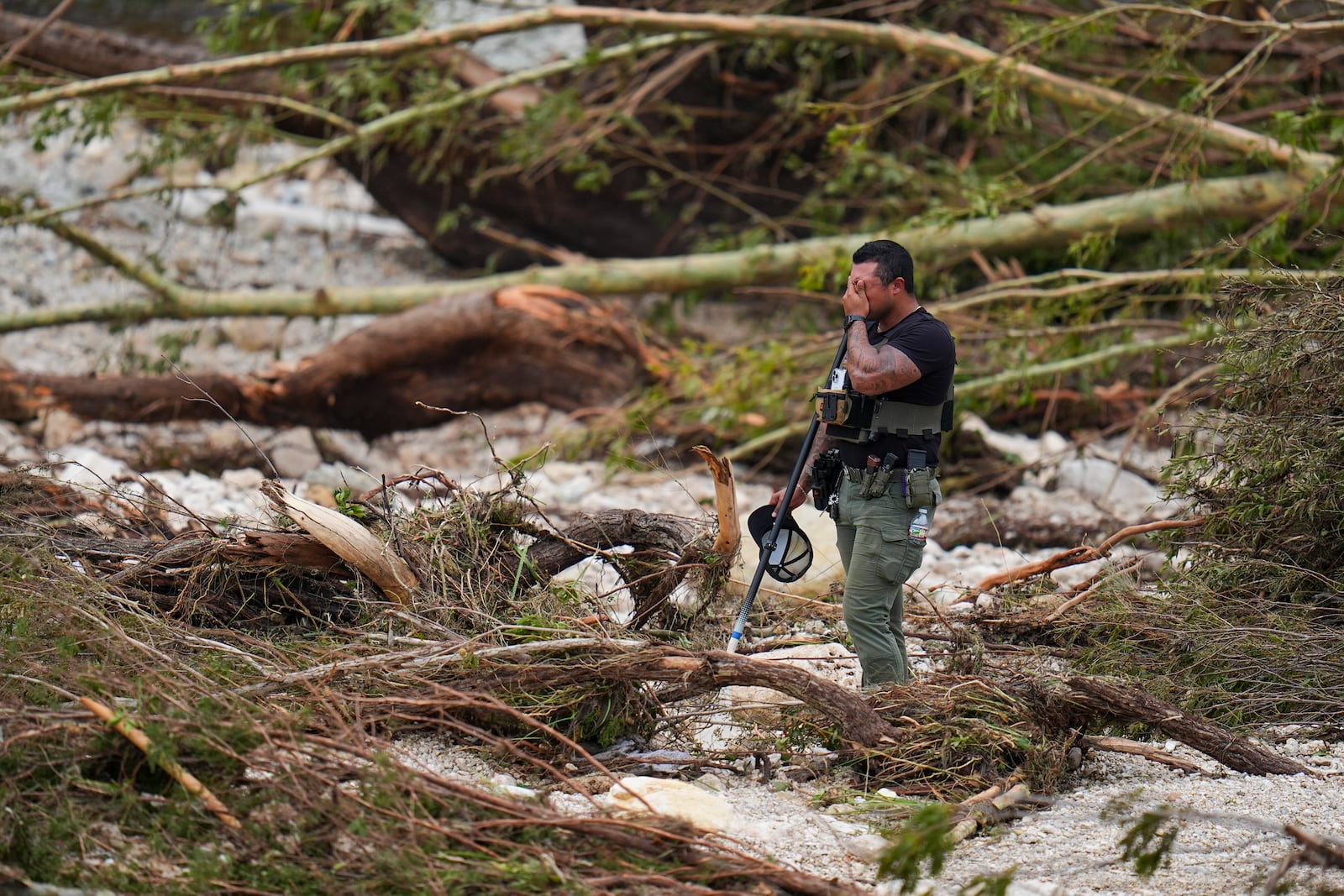 A Sheriff's deputy pauses while combing through the banks of the Guadalupe River near Camp Mystic after a flash flood swept through the area Saturday, July 5, 2025, in Hunt, Texas. (AP Photo/Julio Cortez)