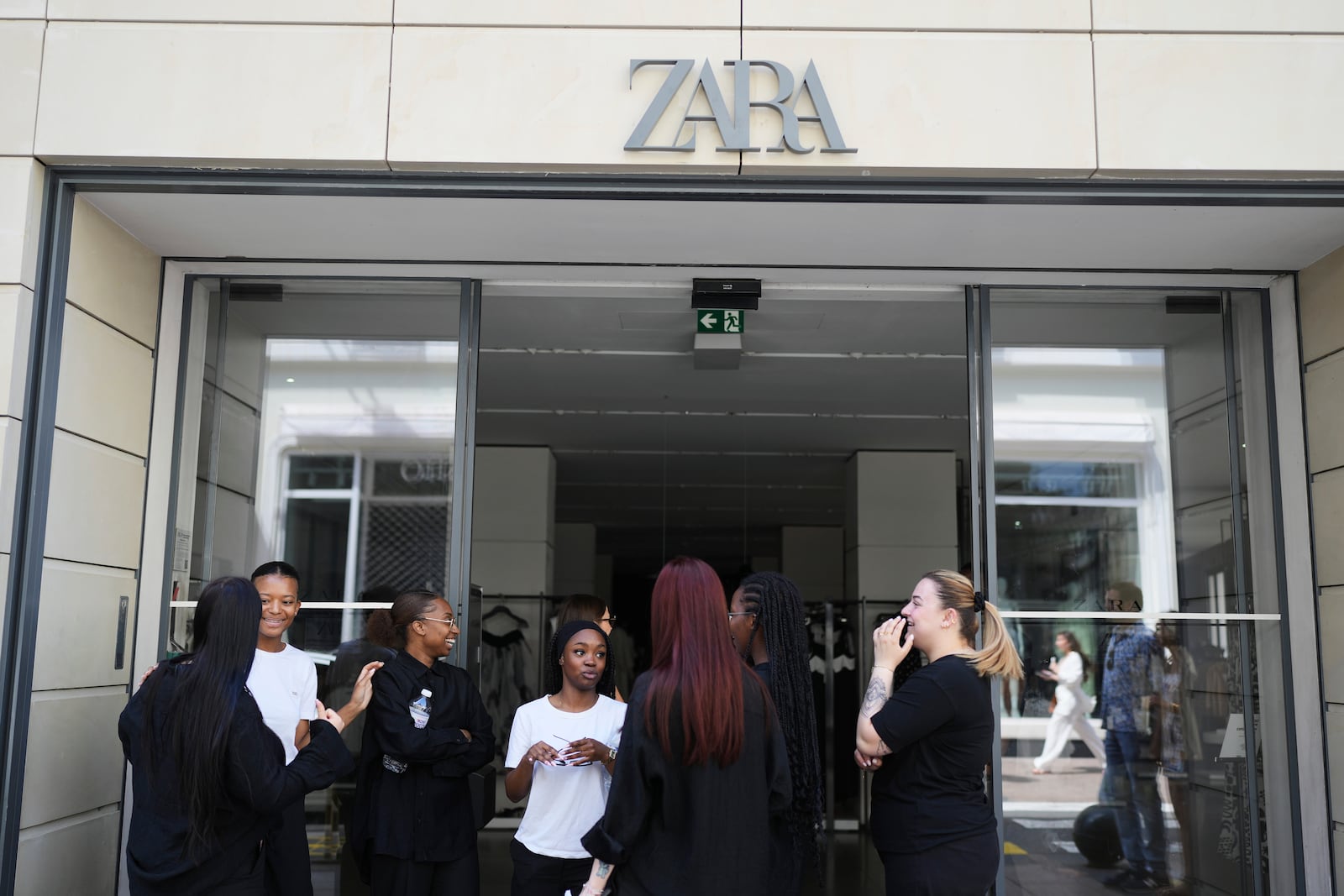 Employees stand outside a shop during an electricity outage in Cannes, southern France, Saturday, May 24, 2025. (AP Photo/Natacha Pisarenko)