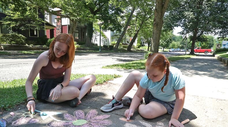 Mary Cunningham, left, and her sister, Helen, brighten up the sidewalk along South Fountain Avenue with chalk drawings of flowers Wednesday, July 13, 2022. BILL LACKEY/STAFF