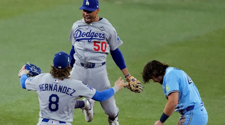 Los Angeles Dodgers' Mookie Betts (50) leaps into the arms of Kiké Hernández (8) after Toronto Blue Jays' Addison Barger, right, was forced out to end Game 6 of baseball's World Series, Friday, Oct. 31, 2025, in Toronto. (AP Photo/Ashley Landis)