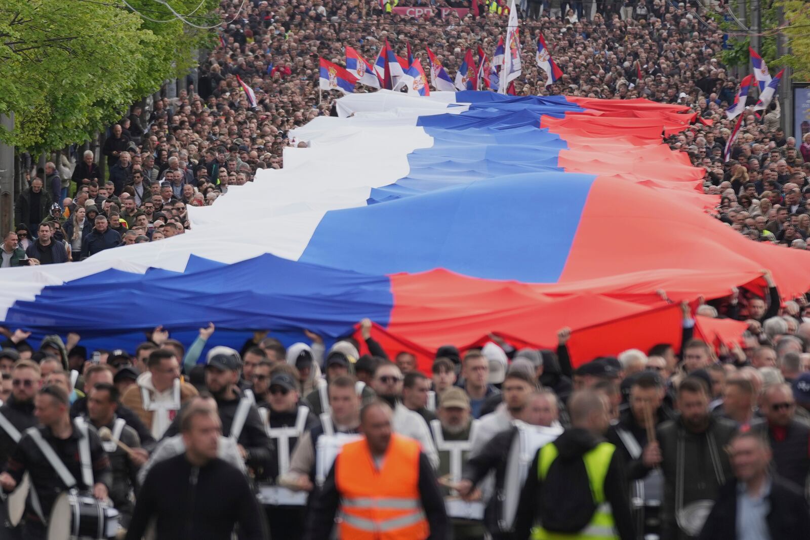 People hold a giant Serbian flag ahead of a big counter-opposition protest rally planned to stage over the weekend in downtown Belgrade, Serbia, Friday, April 11, 2025. (AP Photo/Darko Vojinovic)